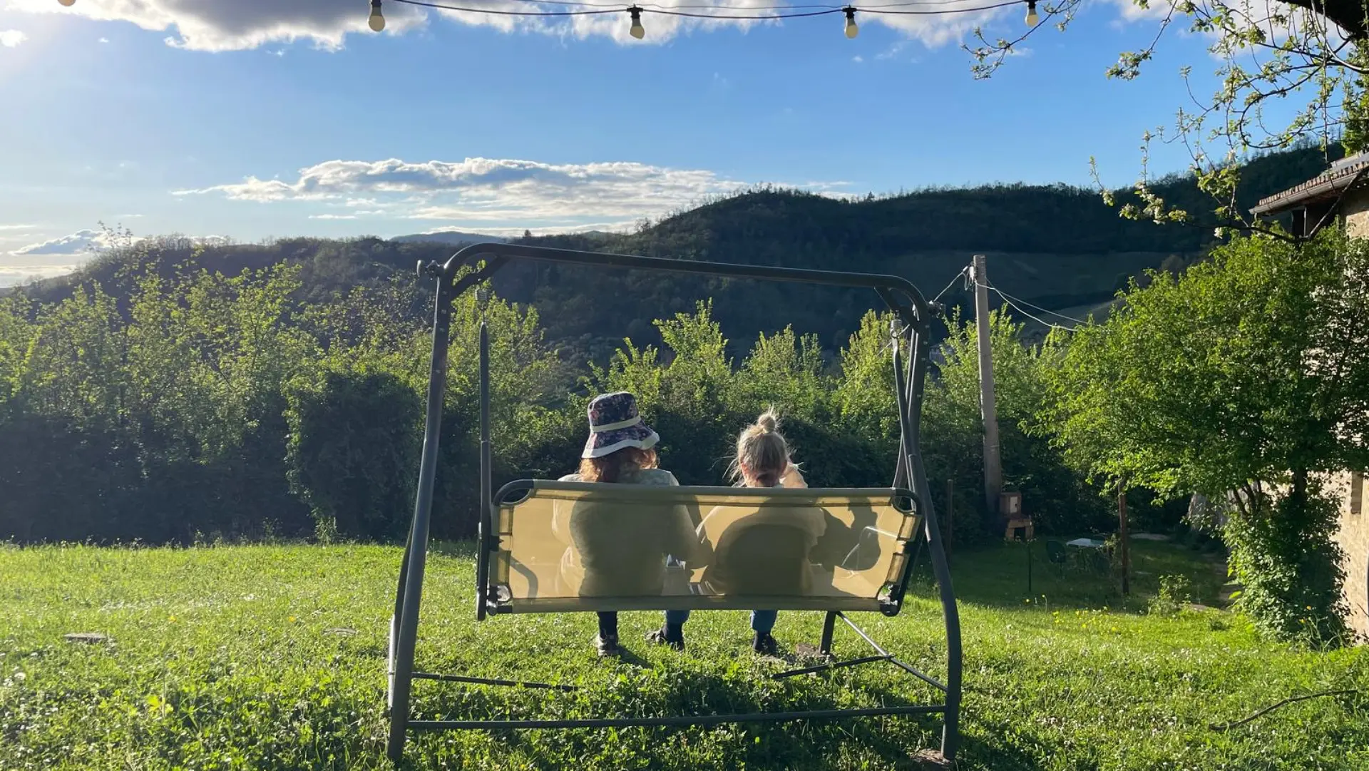 Two retreat guests relaxing on a garden swing with views of the Italian mountains