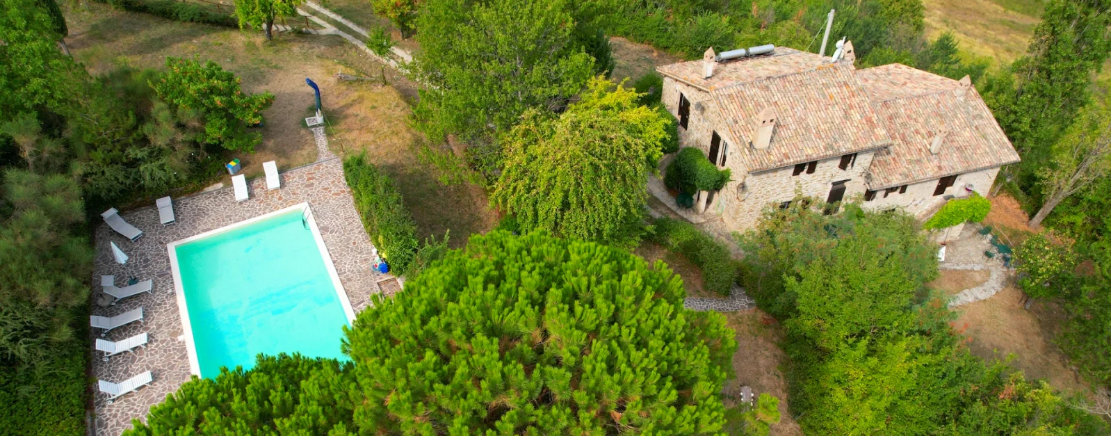 Aerial view of Basaletto stone farmhouses and swimming pool in Italy